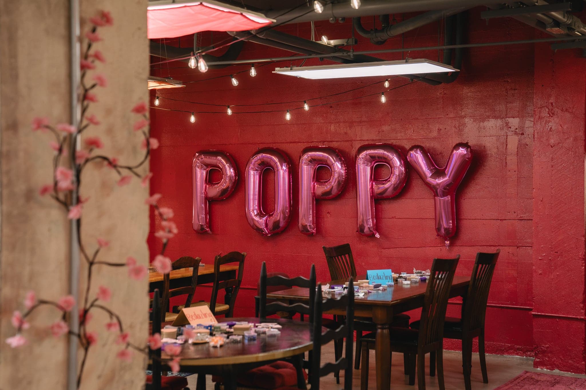 The red room at Poppy House with pink POPPY balloons over the tables