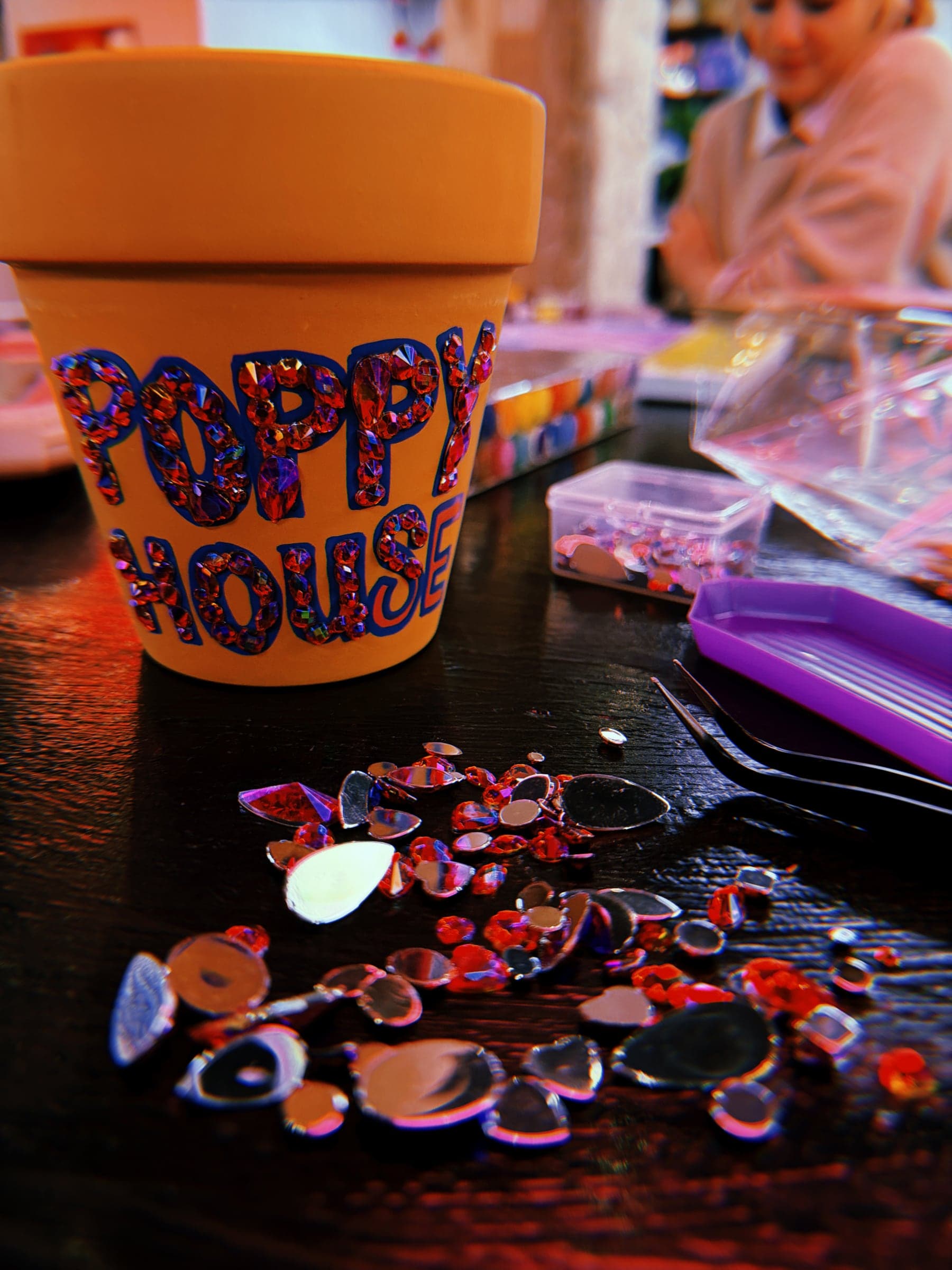 A flower pot covered in rhinestones that spell Poppy House